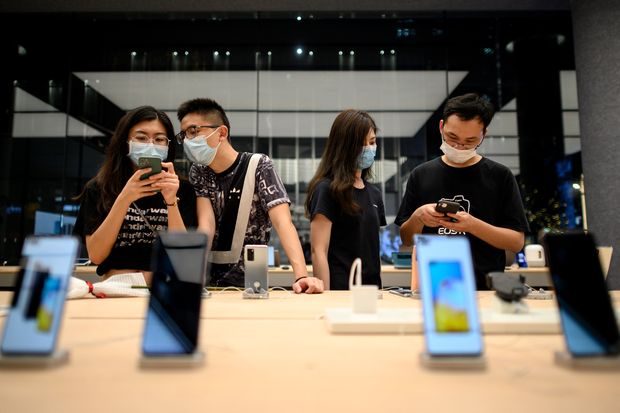Prospective customers look at smartphones on display at Huawei's flagship store in Shenzhen, China, in...